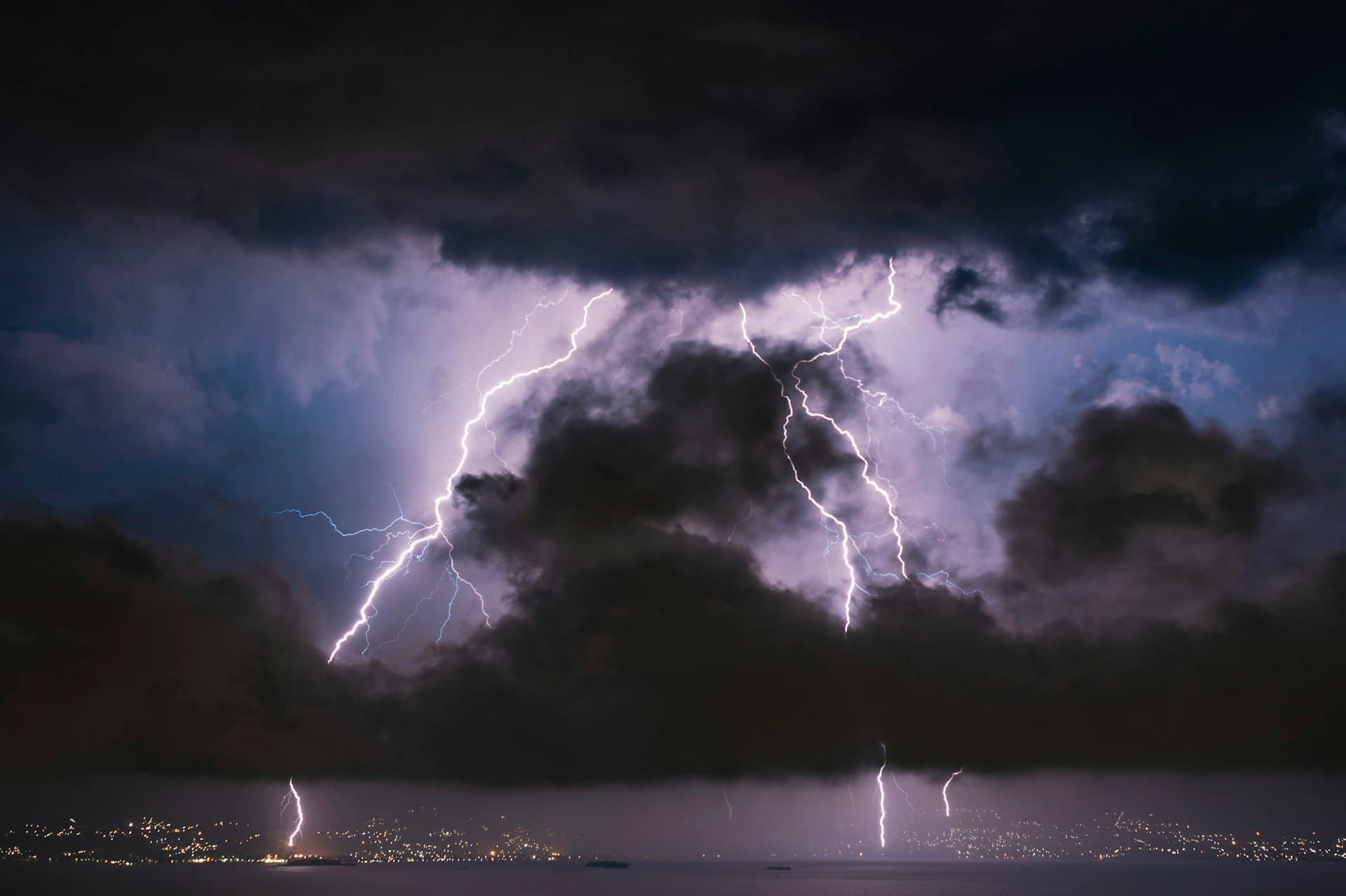 Lightning striking over the water at night